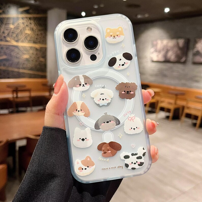 May include: Clear phone case decorated with various cartoon dog illustrations. The case has a light blue border and features a magnetic ring. The phrase "Have a nice day" is printed on the case.