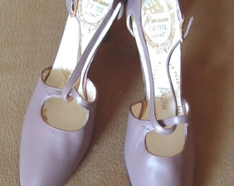 May include: A pair of mauve leather heeled shoes with a strap across the instep. The shoes have a gold label on the inside that reads "A's 2000 De Mi Love".