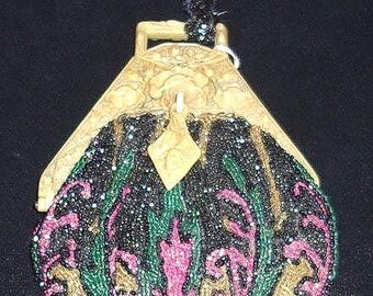 May include: A vintage beaded purse with a gold-colored frame and a dark blue velvet handle. The purse features a black background with pink, green, and gold floral embroidery. The clasp is a diamond shape.