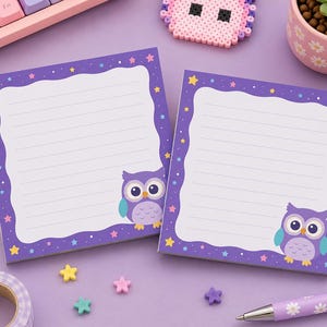 May include: Two square sticky note pads with a purple border featuring a white scalloped centre with horizontal lines. Each pad displays a cartoon owl with large eyes and colourful stars scattered along the purple frame on a light purple surface.