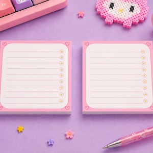 May include: Two rectangular sticky note pads with a white lined interior, a pink border, and small heart icons in the corners. Each line on the paper is marked with a tiny yellow and white flower icon on the right side, set against a purple background.