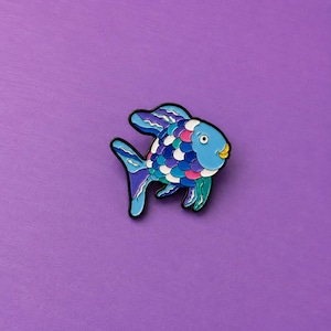 Peut inclure: Une broche en émail métallique en forme de poisson avec une tête bleu clair et une bouche jaune. Le corps présente un motif d'écailles superposées dans des tons de bleu, violet, rose et blanc. Les nageoires sont bordées de noir avec des détails bleus et blancs.