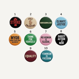 May include: A collection of ten circular pin-back buttons featuring various colors and text. The buttons display slogans including STRIKE, FREE PALESTINE, BIOREGIONALISM, CLIMATE JUSTICE, MYOB, THINK FOR YOURSELF, NO HUMAN IS ILLEGAL, DIRECT ACTION NOW, EQUALITY, and FEMINISM IS FREEDOM.