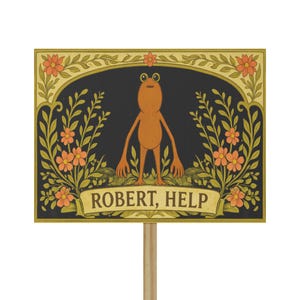 May include: A rectangular sign featuring a cartoon frog with the text "ROBERT, HELP". The sign has a black background with floral and leaf accents in gold and orange. The frog is orange and stands on a bed of green leaves.