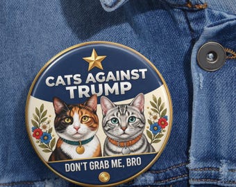 Puede incluir: Una chapa redonda con fondo azul oscuro y crema y una estrella dorada en la parte superior. Muestra dos gatos, uno tricolor y otro atigrado plateado, rodeados de motivos florales. El texto dice CATS AGAINST TRUMP y DON'T GRAB ME, BRO.