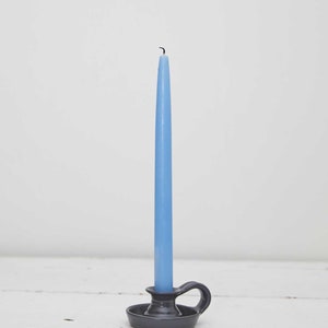May include: A blue candle in a gray ceramic candlestick with a handle.