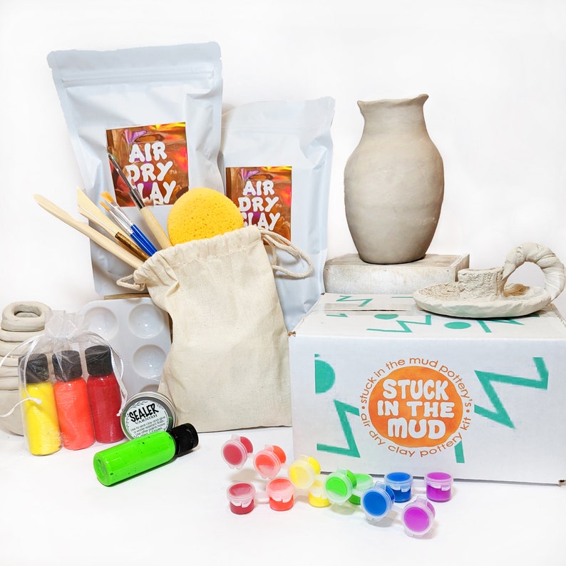 May include: A pottery kit with air dry clay, paint, brushes, and a sponge. The kit includes a vase, a small ceramic piece, and a box with the text "Stuck in the Mud pottery's air dry clay pottery kit".