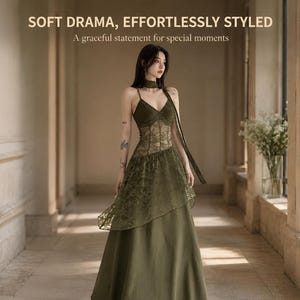 May include: An olive green floor-length dress featuring a V-neckline, thin spaghetti straps, a lace bodice overlay, and an asymmetrical lace skirt panel. The text reads: SOFT DRAMA, EFFORTLESSLY STYLED. A graceful statement for special moments.