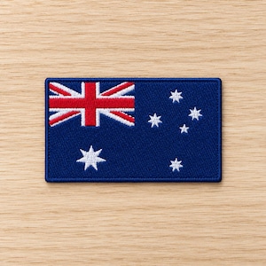May include: A rectangular embroidered patch featuring the flag of Australia. The design includes a dark blue background with the Union Jack in the upper left corner, a large seven-pointed Commonwealth Star below it, and five smaller white stars.