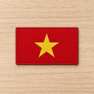 May include: A rectangular embroidered patch featuring a solid red background with a single, centred, five-pointed yellow star. The patch has a stitched border in a matching red thread, creating a clean, defined edge for this flag-inspired design.