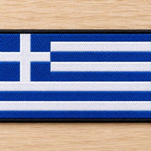 Peut inclure: Un écusson rectangulaire brodé représentant le drapeau national de la Grèce. Le motif se compose de neuf bandes horizontales alternant bleu et blanc, avec une croix blanche sur un carré bleu dans le coin supérieur gauche et une bordure noire.