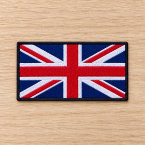 Puede incluir: Un parche rectangular bordado con el diseño de la bandera Union Jack. El parche muestra el icónico patrón en rojo, blanco y azul con un borde negro grueso que rodea todo el contorno, exhibiendo costuras detalladas en toda la tela.