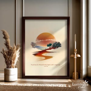 Può includere: Stampa artistica incorniciata raffigurante un paesaggio con un grande sole arancione, un sentiero tortuoso e alberi. È presente la citazione "Un viaggio di mille miglia inizia con un singolo passo". L'opera è in una cornice marrone scuro.