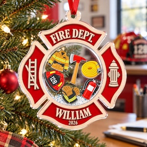 May include: A clear acrylic Christmas ornament shaped like a Maltese cross with red accents. It features the text FIRE DEPT, WILLIAM, and 2026. Inside are illustrations of a yellow jacket, red helmet with 128, axe, hose, gloves, and hydrant.
