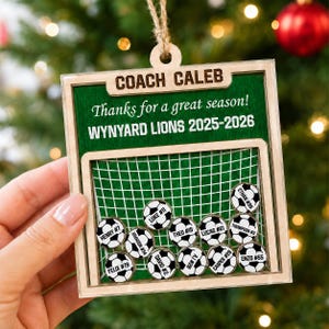 May include: A square wooden ornament featuring a green background with the text COACH CALEB, Thanks for a great season!, and WYNYARD LIONS 2025-2026. It includes a soccer goal graphic with eleven small soccer ball tokens labeled with names and numbers.