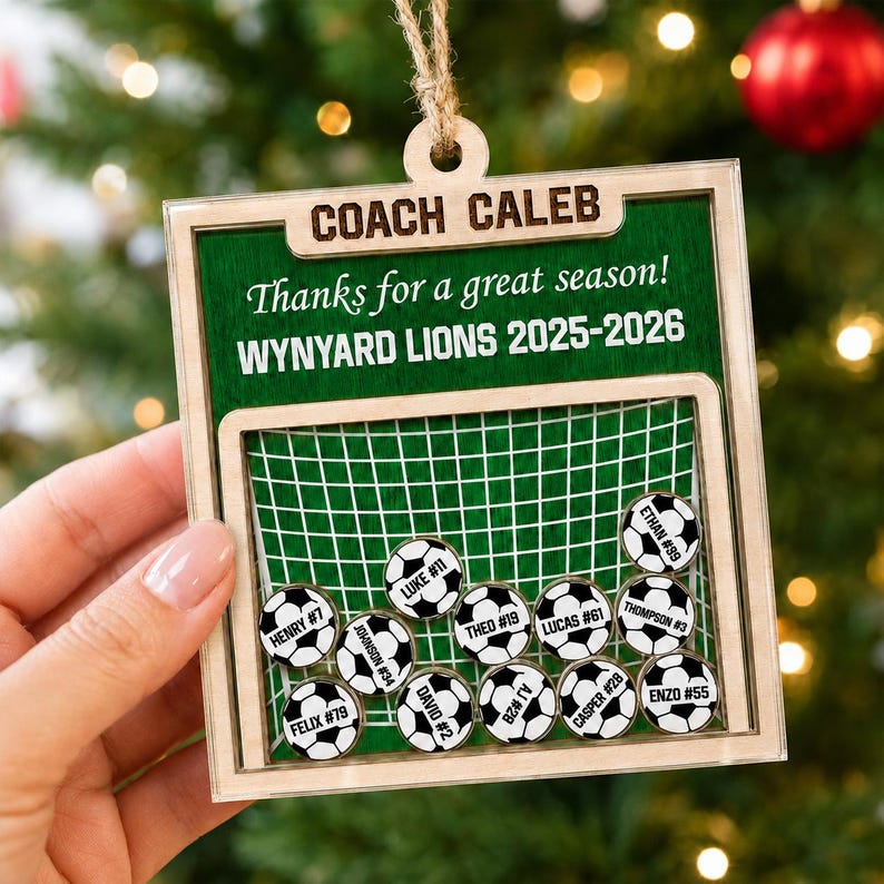 May include: A square wooden ornament featuring a green background with the text COACH CALEB, Thanks for a great season!, and WYNYARD LIONS 2025-2026. It includes a soccer goal graphic with eleven small soccer ball tokens labeled with names and numbers.