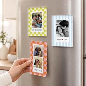 May include: Three rectangular acrylic photo frames with magnetic backs. One has a lime green checkerboard border with "THE SMITH FAMILY" text. One has a light blue striped border with "Henry &hearts; Alice" text. One has a wavy orange and pink checkerboard border with "SOPHIA & LUCAS" text.