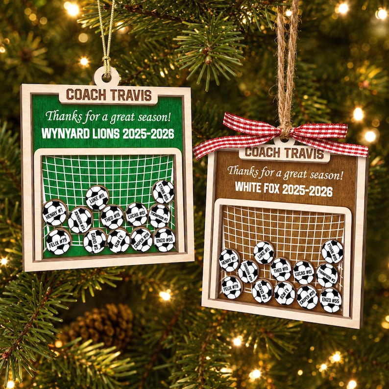 May include: Two square wooden ornaments featuring a soccer goal graphic. The left ornament is green with text reading COACH TRAVIS, Thanks for a great season!, WYNYARD LIONS 2025-2026. The right is brown with a red gingham bow and matching text.