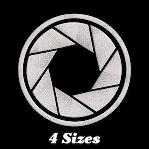 May include: White embroidered camera lens aperture design on a black background. 4 Sizes.
