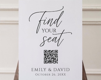 May include: A white sign on a wooden easel with the words "Find Your Seat" in elegant black script. Below the text is a QR code and the names "Emily & David" with the date "October 26, 20XX".