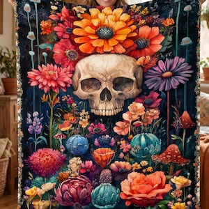May include: A rectangular throw blanket featuring a central human skull surrounded by a vibrant array of colorful flowers, including large orange, red, pink, and purple blossoms, along with small mushrooms and teal succulents on a dark background.