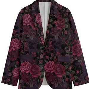 May include: A floral blazer featuring a dark purple background with a pattern of burgundy roses and green leaves. The blazer has a single-button closure, two pockets, and a white interior lining. This jacket is a stylish addition to any wardrobe.