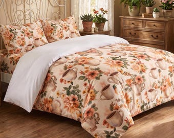May include: A bedding set featuring a duvet cover and two pillowcases with a cream background, decorated with a repeating pattern of orange and peach-colored flowers, green leaves, and light brown coffee mugs filled with steaming hot beverages.