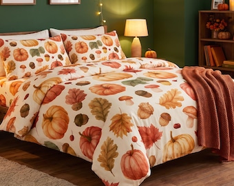 May include: A bedding set featuring a cream-colored duvet cover and two matching pillowcases decorated with a repeating watercolor pattern of orange pumpkins, brown acorns, and multicolored autumn leaves, paired with a solid burnt orange throw blanket.