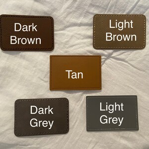 May include: Five leather swatches in different colors: dark brown, light brown, tan, dark grey, and light grey. Each swatch has the color name written in white text.