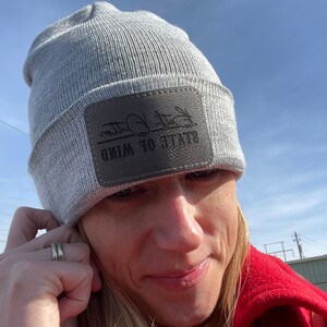 May include: Gray beanie with a brown leather patch that says "State of Mind" in black lettering.