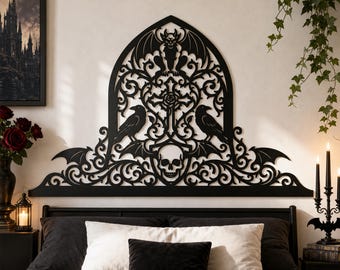 May include: A black, laser-cut wall art piece featuring a gothic arch design with a central cross, a skull at the base, two ravens on either side, and a gargoyle at the top. The intricate filigree pattern includes bat wings and scrolling vines.