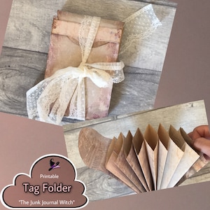 May include: A printable tag folder with a floral design, tied with a white lace ribbon. The folder is made of aged paper and has a vintage aesthetic. The text "Tag Folder" and "The Junk Journal Witch" are visible.