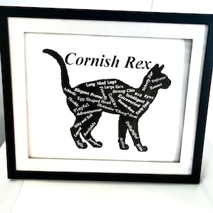 May include: A framed black and white print featuring a silhouette of a Cornish Rex cat. The cat's outline is filled with descriptive words like "athletic," "playful," and "extroverted." The words are in a white font. The frame is black.