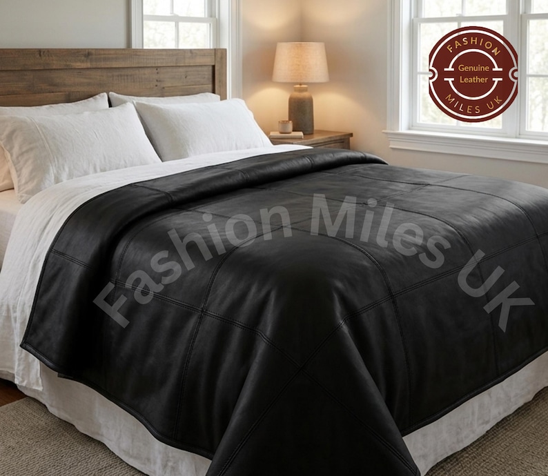 May include: A black leather bedspread featuring a grid-like stitched pattern. The bedspread is draped over a bed with white pillows and a white bed skirt. A circular logo in the corner reads Fashion Miles UK Genuine Leather.