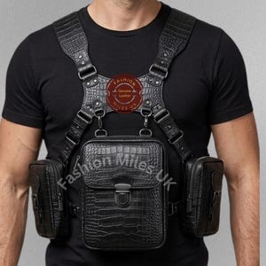 Peut inclure: Harnais de poitrine en cuir noir avec une texture peau de crocodile. Le harnais comporte plusieurs pochettes et sangles, avec le texte "Fashion Miles UK" visible. Un emblème circulaire indique "Fashion Miles UK Genuine Leather".