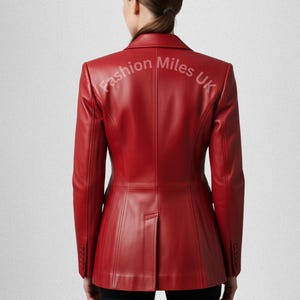 May include: A vibrant red leather blazer with a classic tailored design. The jacket features a notched lapel, buttoned cuffs, and a single-button closure. The text "Fashion Miles UK" is printed on the back of the blazer.