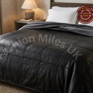 May include: A black leather bedspread featuring a grid-like patchwork design with visible stitching. The bedspread is draped over a bed with white pillows. A circular logo in the corner contains the text Fashion Miles UK Genuine Leather.
