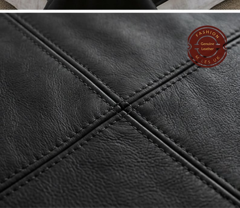 May include: A black leather surface with a textured grain and a cross-stitched pattern featuring double rows of stitching. A circular red stamp in the upper right corner contains the text FASHION, Genuine Leather, and M LES UK in white lettering.