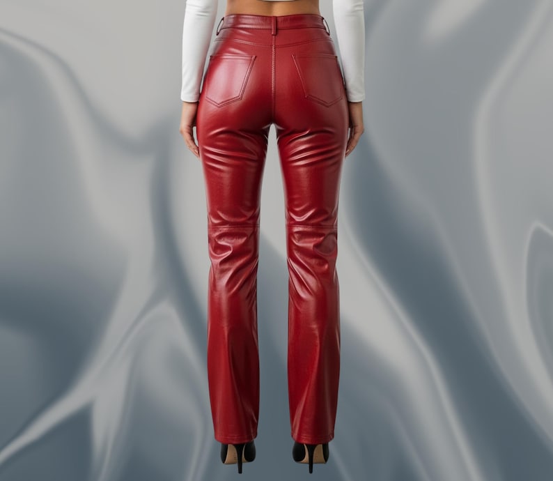 May include: A pair of red leather pants with a high waist and a flared leg. The pants have two back pockets and a zipper closure. The model is wearing black high heels. The pants are made of a shiny, smooth material.