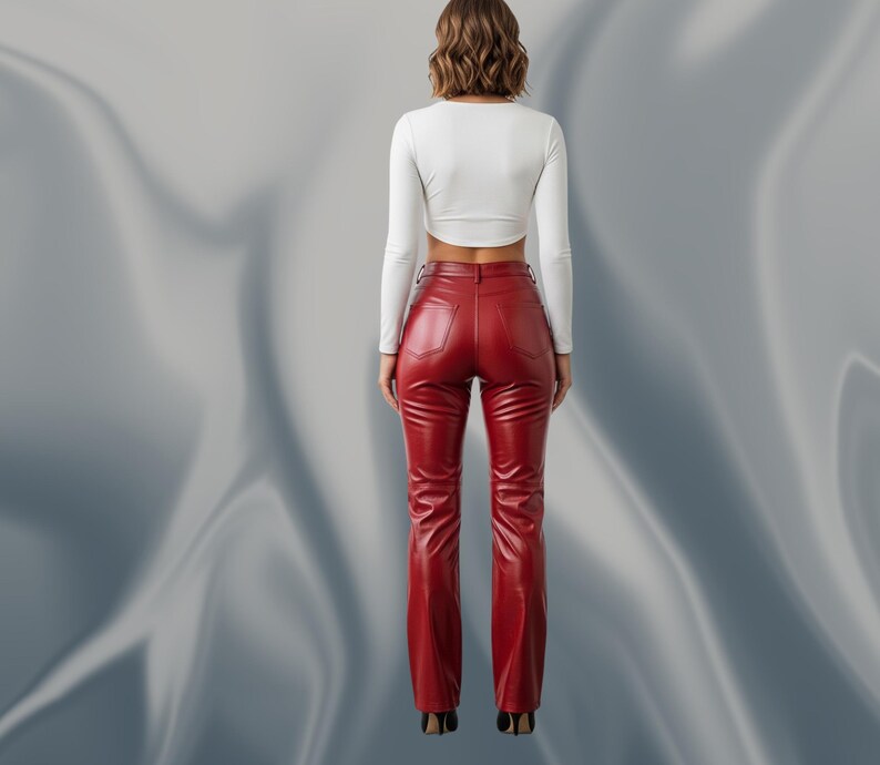 May include: A woman wearing a white long-sleeve crop top and red leather pants. The pants are high-waisted with a flared leg. The outfit is shown from the back against a silver background.