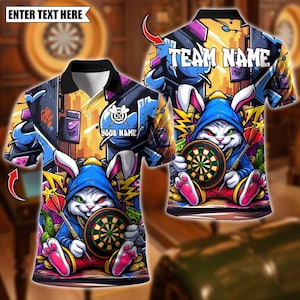 May include: A polo shirt with a cartoon rabbit in a blue hoodie, holding a dartboard and darts. The shirt has a graffiti-style design with the words "TEAM NAME" and "YOUR NAME". The background is a mix of yellow, blue, and purple.