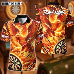 Op de afbeelding: Een poloshirt met een vurige phoenix-design, pijlen en een dartbord. De shirt heeft een zwarte kraag en de tekst "ENTER TEXT HERE", "NAME", "YOUR" en "TEAM NAME". Het ontwerp is voornamelijk oranje en geel.