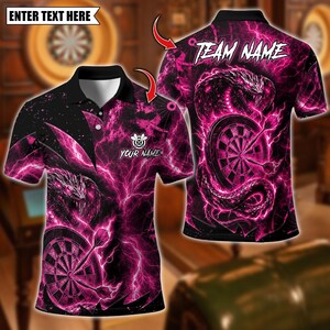 May include: A black and pink polo shirt featuring a graphic of a snake coiled around a dartboard with lightning patterns. The front displays the text "YOUR NAME" and the back features the text "TEAM NAME" with a placeholder for "ENTER TEXT HERE".
