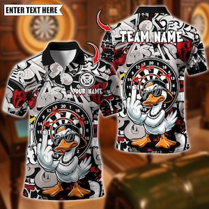 May include: A black polo shirt with a white, red, and gray graffiti-style design. The shirt features a cartoon duck wearing sunglasses and a hat, giving the middle finger. The text "TEAM NAME" and "YOUR NAME" are visible.