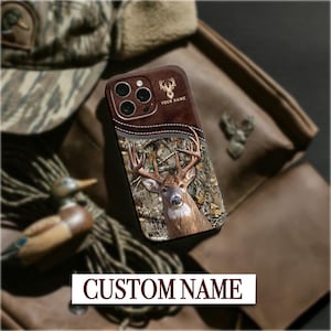 May include: A brown leather phone case with a deer graphic and camouflage pattern. The case has a zipper design and the text "YOUR NAME" and "CUSTOM NAME".