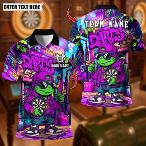 Könnte beinhalten: Ein lila-schwarzes Poloshirt mit einer Zeichentrickschildkröte mit Sonnenbrille und lila Kapuzenpullover, die einen Dart und eine Dartscheibe hält. Das Shirt hat das Wort "DARTS" im Graffiti-Stil.