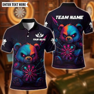 May include: Dark navy polo shirt featuring a colorful, angry bear graphic holding a dartboard. The shirt has a black collar and the text "TEAM NAME" on the back. The front of the shirt has the text "YOUR NAME" and "ENTER TEXT HERE".