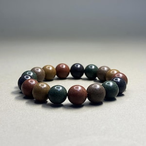 May include: A bracelet made of round, multi-coloured beads. The beads are brown, green, and black.