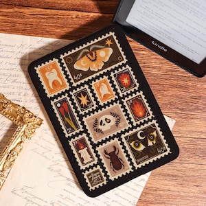 May include: Black rectangular Kindle cover featuring a collage of vintage-style postage stamps. The stamps depict various illustrations, including a moth, skull, and flame, with the text "antique deuce 2822" at the bottom. A Kindle e-reader is visible in the background.