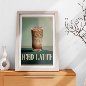 May include: A framed poster with a vintage design featuring a glass of iced latte on a green background. The text "ICED LATTE" is printed in white below the glass.